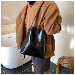 Detail view of large capacity vintage oil wax leather bucket bag worn by a model