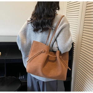 Brown suede tote bag shown on model highlighting its large size and stylish commute design