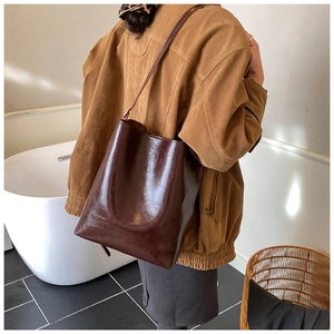 Close-up of glossy wine red leather tote bag with fine texture and minimalist brand logo