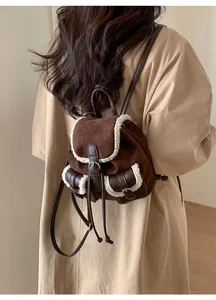 Detail view of brown faux suede backpack with white plush trim and leather straps on model