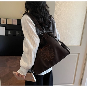 Close-up of brown tote bag with dahlia embroidery and silver adjustable rings