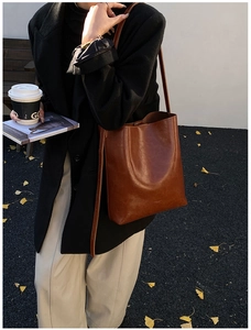 Detail view of large capacity dark brown leather shoulder bag in a stylish autumn setting