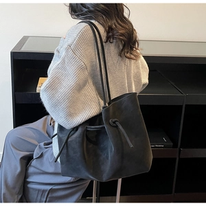 Detail of matte black tote bag with drawstring closure and soft shoulder straps