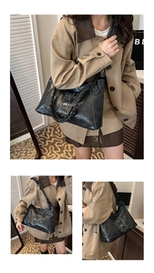 Detail of black PU leather tote bag with white artistic letters and woven handle