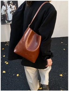 Brown leather bucket bag styled with a black blazer for a modern casual winter fashion look