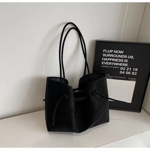 Detail shot of the black suede bucket tote bag showing rope straps and drawstring knots