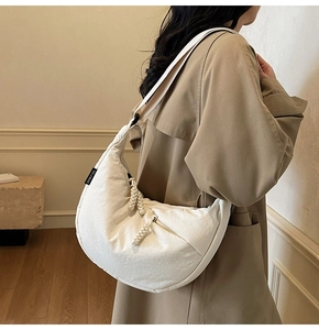 Detailed close-up of white quilted dumpling crossbody bag with braided rope accents