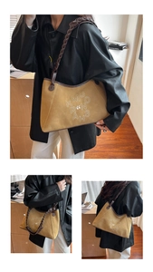 Detail view of brown suede tote bag featuring white letters and woven shoulder strap