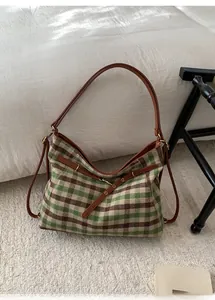 Detail view of retro green checkered shoulder bag with brown leather straps and gold buckles