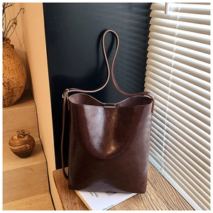 Detailed view of large dark brown wax leather bucket bag with glossy finish and thin straps