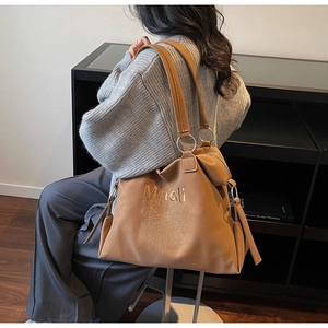 Detail of brown tote bag featuring daisy embroidery and Maidi logo for women