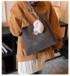 Detail of taupe suede tote bag with plush rabbit charm and metal ring strap link