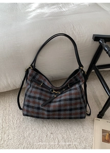 Detail of vintage plaid tote bag with thick fabric texture and black leather handles
