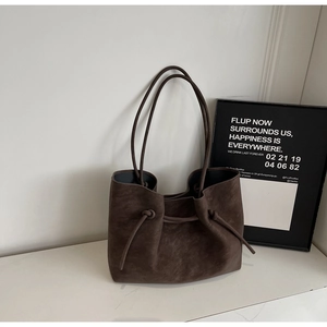 Macro shot of dark coffee suede tote bag with decorative side drawstring detail