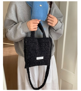 Detailed view of black fuzzy tote bag with brand label and long shoulder strap