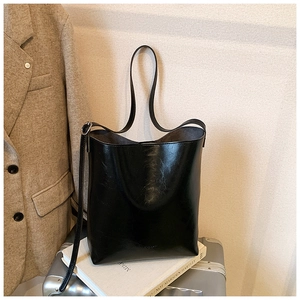 Close-up of a glossy black leather tote bag on a suitcase for office commute and travel