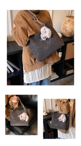 Detail of dark grey tote bag with silver chain strap and plush rabbit charm