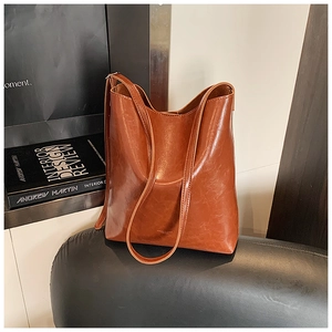 Detailed view of caramel brown glossy leather bucket bag with retro oil wax finish texture