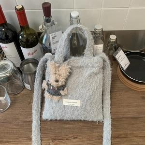 Close-up of grey plush tote bag with brand label and cute puppy pendant accessory