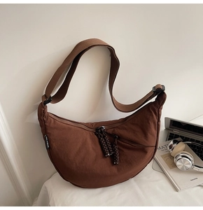 Detail view of a brown nylon crescent bag featuring a woven strap and adjustable buckle