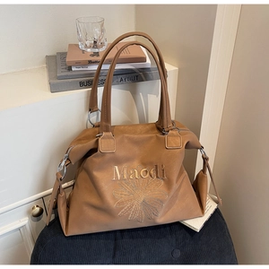 Detail of brown PU leather tote bag with daisy embroidery and metal ring hardware