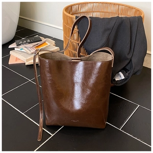 Detail of dark brown leather bucket bag with adjustable strap in luxury lifestyle setting