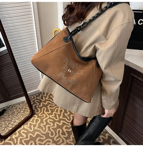 Detail view of brown suede tote bag with white letter embroidery and chain strap