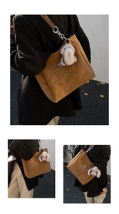 Detail of a brown suede tote bag with a silver chain strap and a plush bunny charm