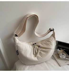 Detail shot of off-white minimalist canvas half-moon bag with braided rope zipper pull