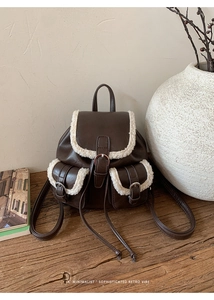 Detailed view of brown faux leather backpack with white sherpa trim and drawstring closure