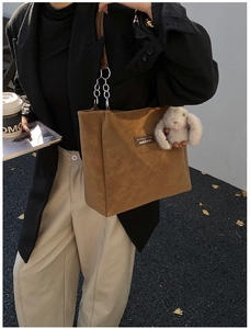 Brown leather tote bag featuring a chain strap and cute plush rabbit keychain accessory