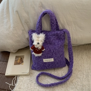 Detail of purple faux fur tote bag with plush puppy charm and soft textile texture