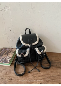 Detail of black leather backpack with white faux fur trim and metallic buckle closure