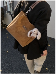 Close-up of brown suede tote bag with leather strap and cute rabbit plush charm