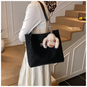 Black suede tote bag detail with chain strap and cute plush rabbit charm on side