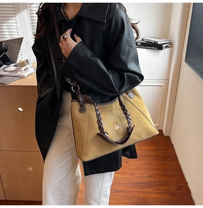 Detail of yellow suede tote bag with brown woven handle worn with a black leather jacket