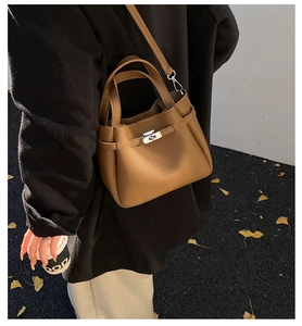 Outdoor shot of a brown pebbled leather bucket bag with metal twist-lock and shoulder strap