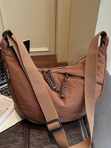 Brown moon-shaped canvas crossbody bag with adjustable wide strap and dual zippers