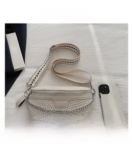 Détail du sac de poitrine tissé beige avec chaîne argentée et sangle géométrique