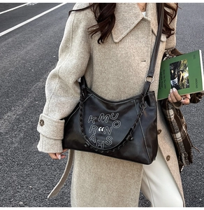 Detail of dark brown leather tote bag with white contrast stitching and adjustable straps