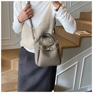 Detail of grey bucket bag with silver metal turn-lock and fine grain texture on stairs