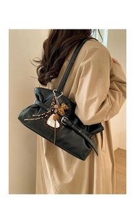 Détail du sac cabas noir en cuir huilé avec design plissé et breloque cœur léopard