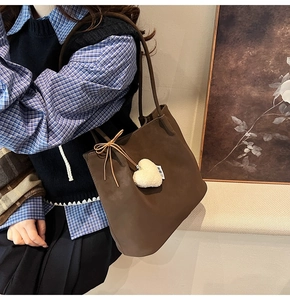 Close-up of vintage dark brown tote bag featuring a white plush heart charm and bow detail