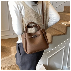 Close-up of brown litchi pattern leather bag with silver swivel lock and handle detail