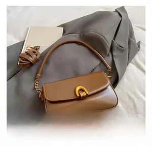 Detailed shot of brown leather shoulder bag featuring a gold horseshoe clasp and soft texture