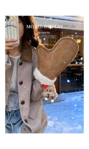 Detail of winter boots-shaped shoulder bag featuring furry dog charm and cozy suede texture