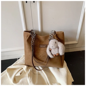 Detail of brown tote bag with silver chain strap and a cute grey plush bunny pendant