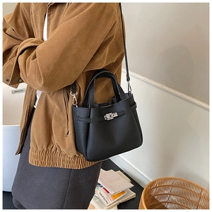 Detail of black lychee grain leather handbag featuring silver twist lock and crossbody strap