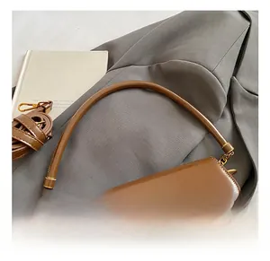 Close-up of brown leather handbag featuring a gold U-shaped metal lock and dual straps