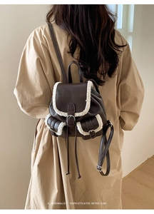 Detail view of brown faux leather backpack with plush fleece trim and retro buckles